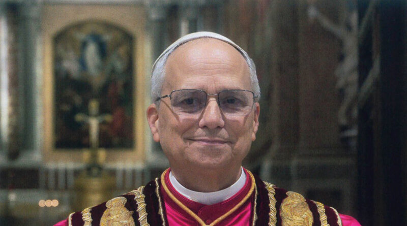 A man wearing glasses and fancy church clothes smiles. He is the new Pope, standing in front of a church altar with a big cross and artwork behind him. He has gray hair and is wearing a white cap.