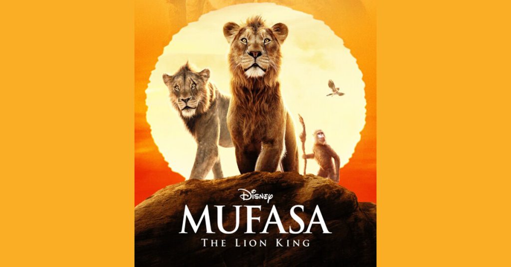 Colorful splash pad with water spraying from buckets, arches, and fountains on a sunny day, with trees and a shaded seating area in the background.