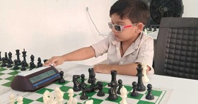 A young boy wearing 3D glasses plays chess and presses a button on a chess clock during a game.