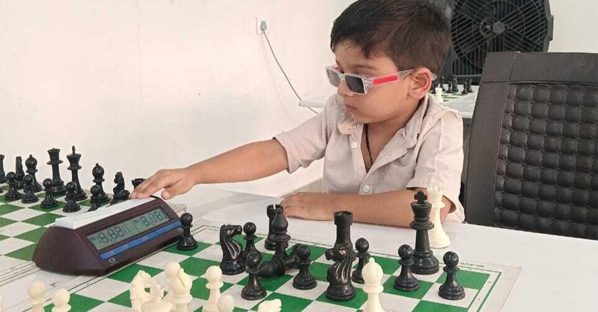 A young boy wearing 3D glasses plays chess and presses a button on a chess clock during a game.