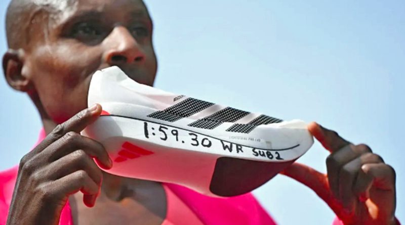 Runner wearing pink holds up a white running shoe with black stripes and "1:59.30 WR SUB2" written on the bottom in marker.