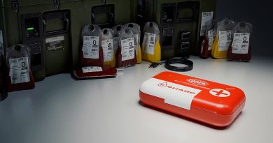 Red and white medical kit labeled 'DARPA SHARP' on a table next to several bags of donated blood in different types.