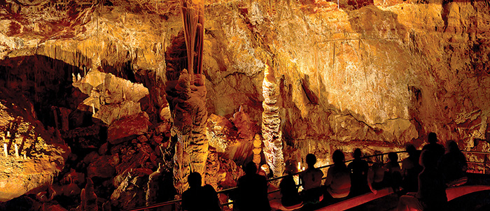 Tan and brown cave walls covered with layered, rippling rock formations that look like melted candle wax.