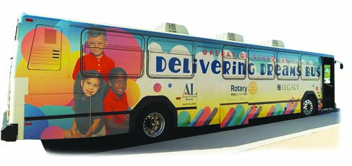 "Colorful bus wrapped in bright artwork with children's faces and the words “Delivering Dreams Bus“.