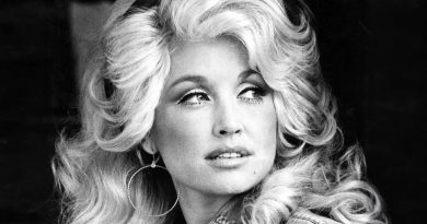 Black and white photo of a Dolly Parton with big, voluminous curly blonde hair and large hoop earrings, looking to the side.