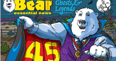 Bear Essential News October 2026 Edition. Boomer, a polar bear dressed as Dracula holds open a red cape that says “45 Years” and a pumpkin candy bucket on a spooky night.